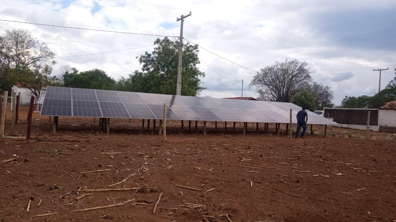 Painéis solares instalados em uma estrutura no solo, em uma área aberta.